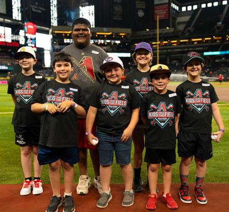 7 winners of the Kids take the field giveaway from the Husband and Wife Law Team together on field before the game