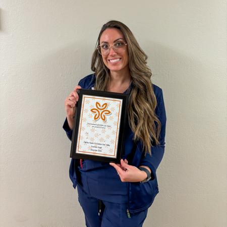 Nurse Janell smiling and holding her Guardian Angel plaque