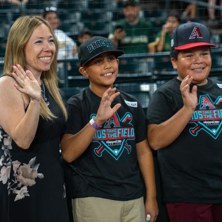 Alexis Breyer with 2 happy kids on Chase Field waving to the crowd.