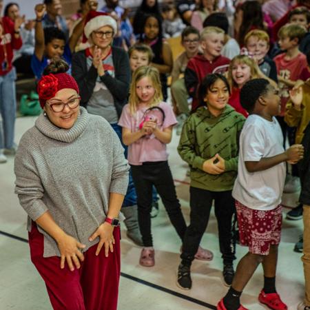 Surprised teacher walking to accept her award while students cheer