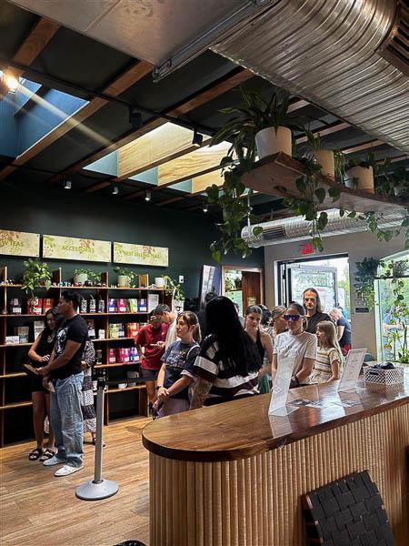 Customers line up inside Scented Leaf, surrounded by lush plants and warm wooden décor.