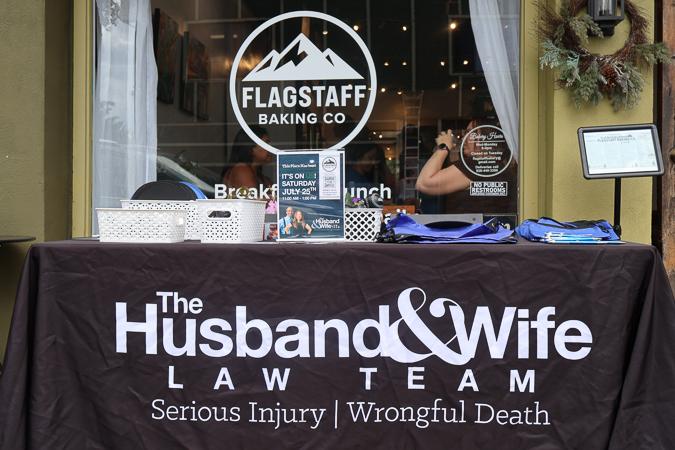 A Husband & Wife Law Team outreach table outside Flagstaff Baking Co. provides information and resources for individuals affected by serious injuries and wrongful death cases.