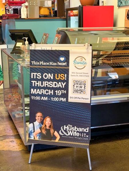 A Husband & Wife Law Team poster near a glass counter promotes an event on March 19th from 11 AM to 1 PM with $15 off per person